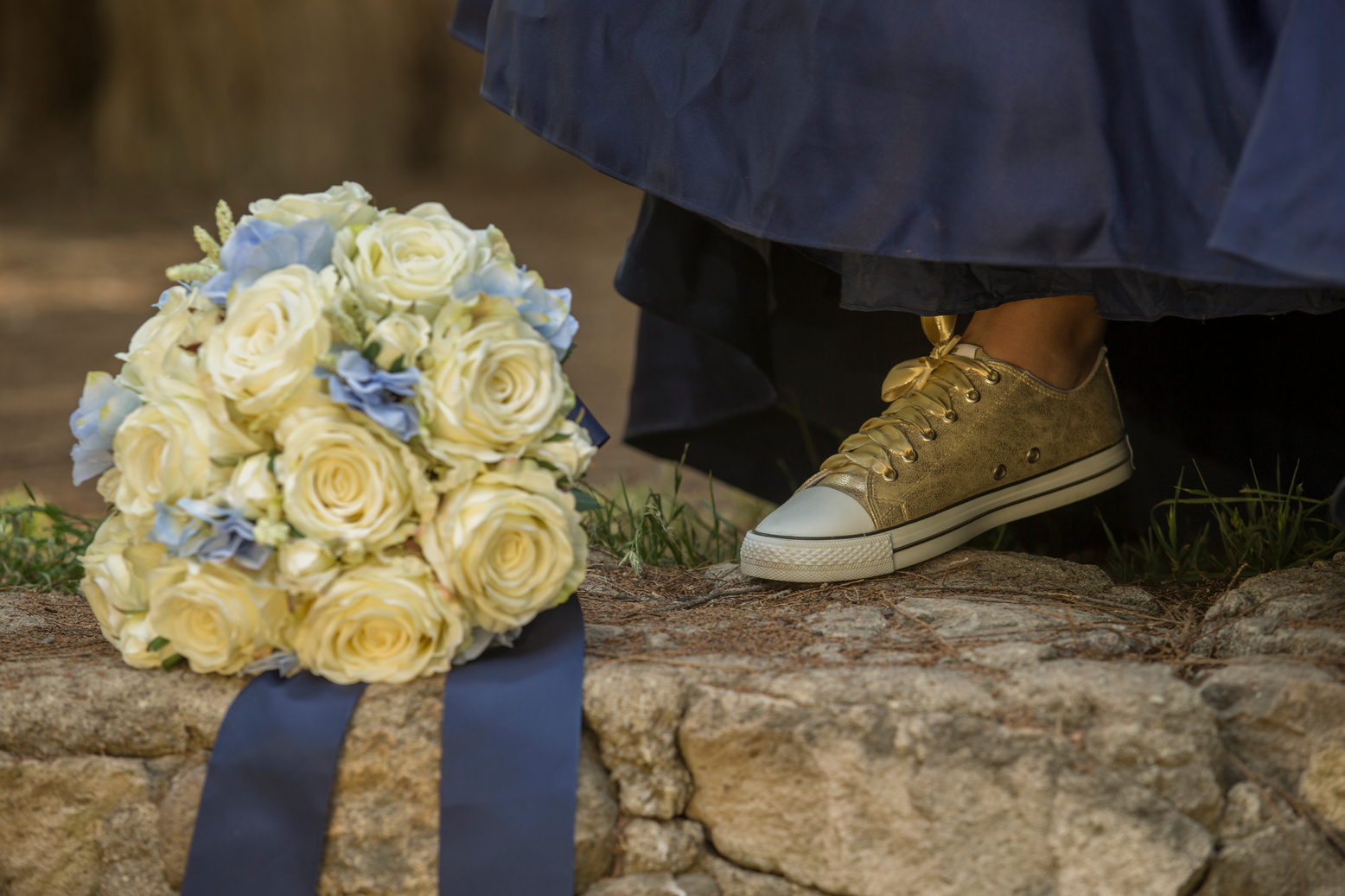 detail of golden tennis shoes, elegant blue dress and a flower arrangement of white roses, fifteen year party concept, fifteen years